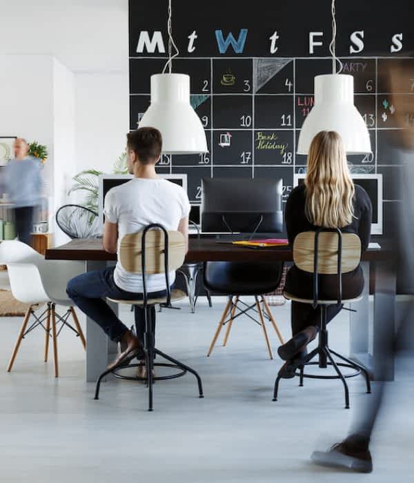 People in modern coworking space with blackboard calendar